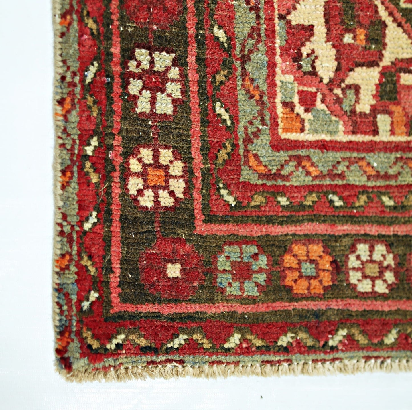A close-up of a vintage Persian Hamadan runner featuring a geometric floral border in wool.