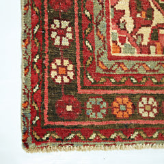 A close-up of a vintage Persian Hamadan runner featuring a geometric floral border in wool.