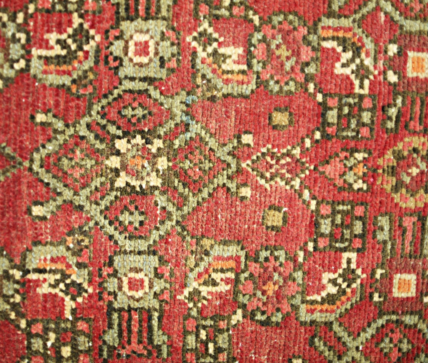 A close-up of a vintage Persian Hamadan runner featuring intricate geometric patterns in red and green.