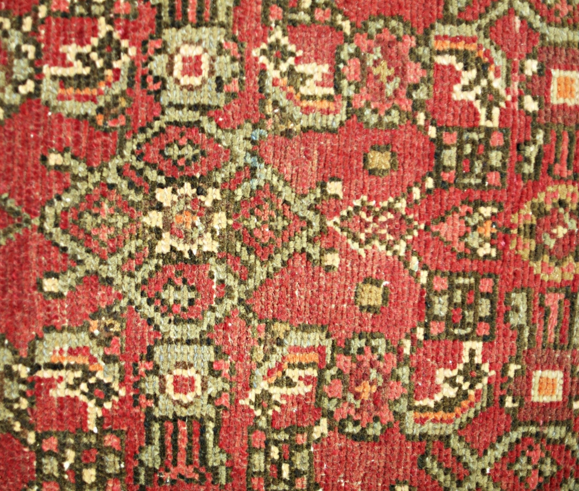 A close-up of a vintage Persian Hamadan runner featuring intricate geometric patterns in red and green.