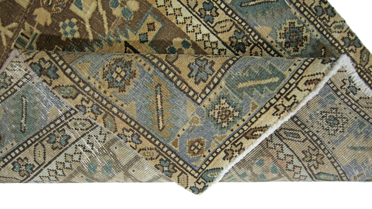A folded vintage Persian Malayer runner featuring intricate geometric patterns in blue and brown.