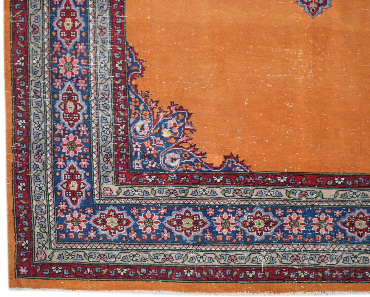 A vintage Persian Mashad rug featuring a bright orange field with intricate blue and red floral borders.