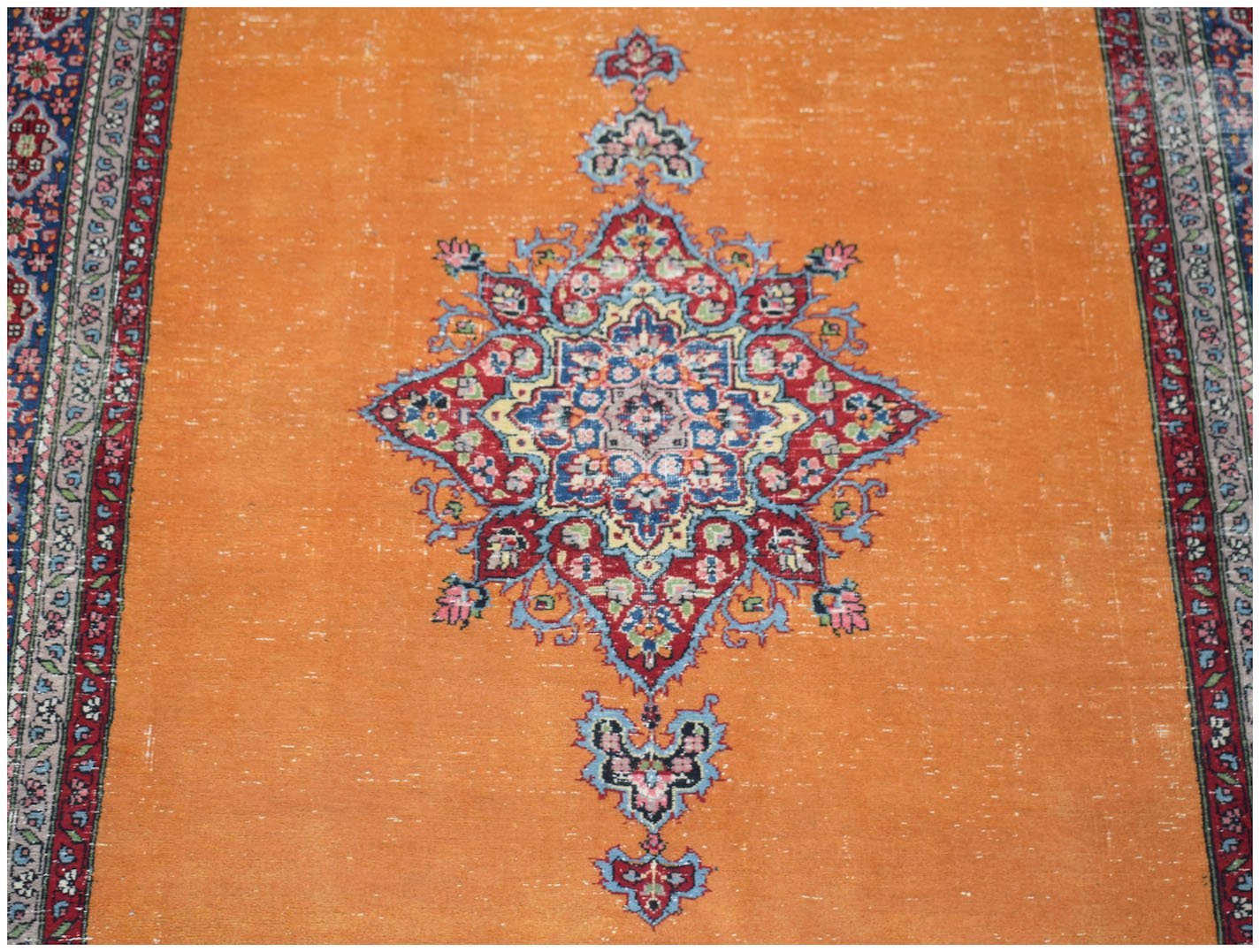 A vintage Persian Mashad rug featuring a central floral medallion on a bright orange field.