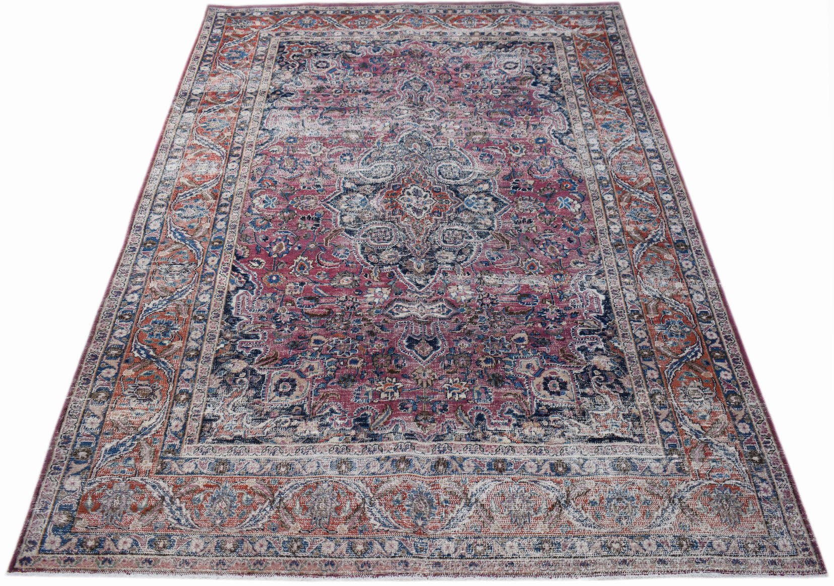 A vintage handwoven Persian Mashhad rug featuring intricate floral patterns in pink and blue tones.