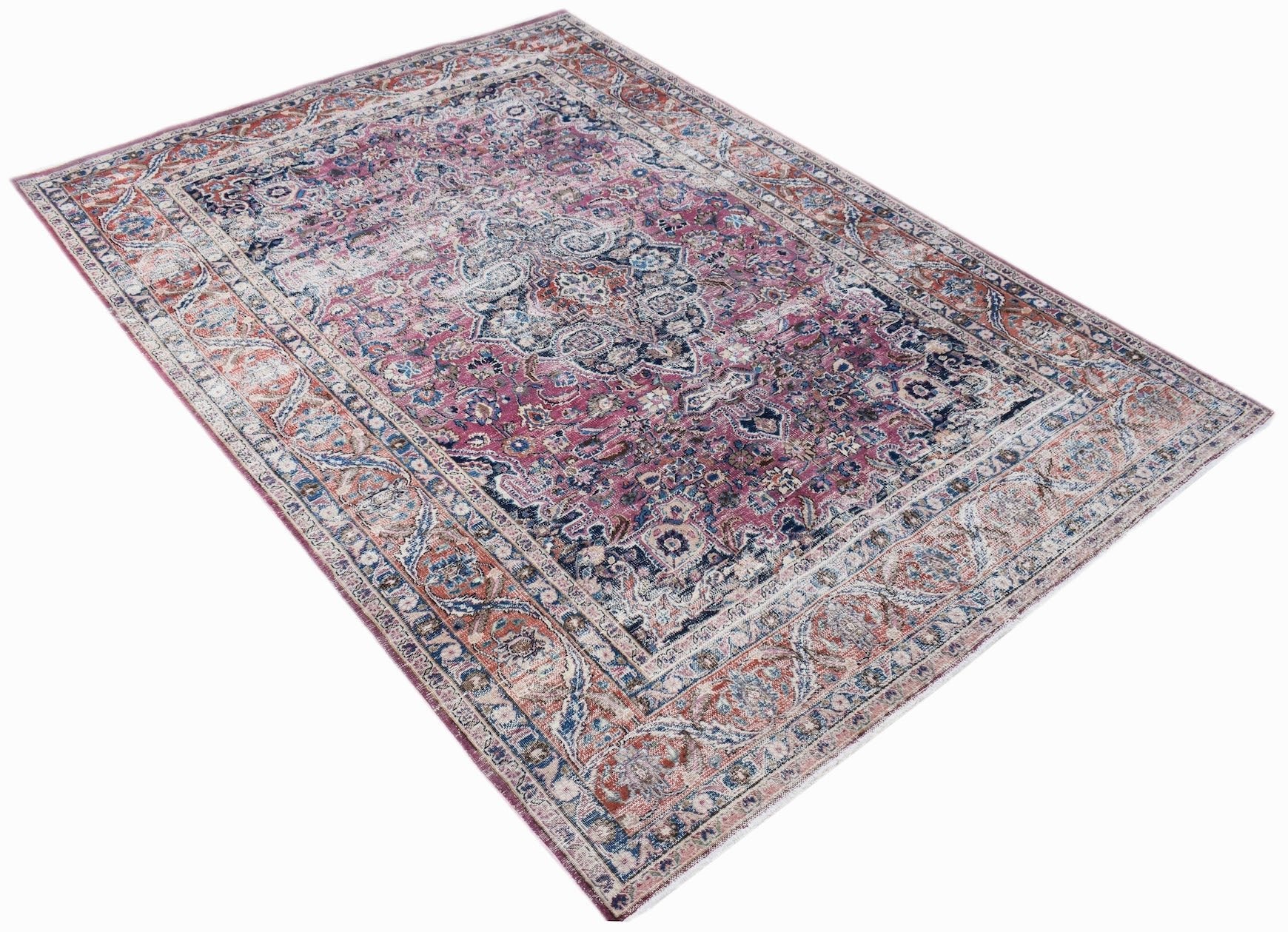 A vintage Persian Mashhad rug featuring intricate floral patterns in shades of pink, blue, and rust.