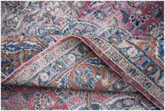 A vintage Persian Mashhad rug featuring intricate floral patterns in shades of pink, blue, and tan.