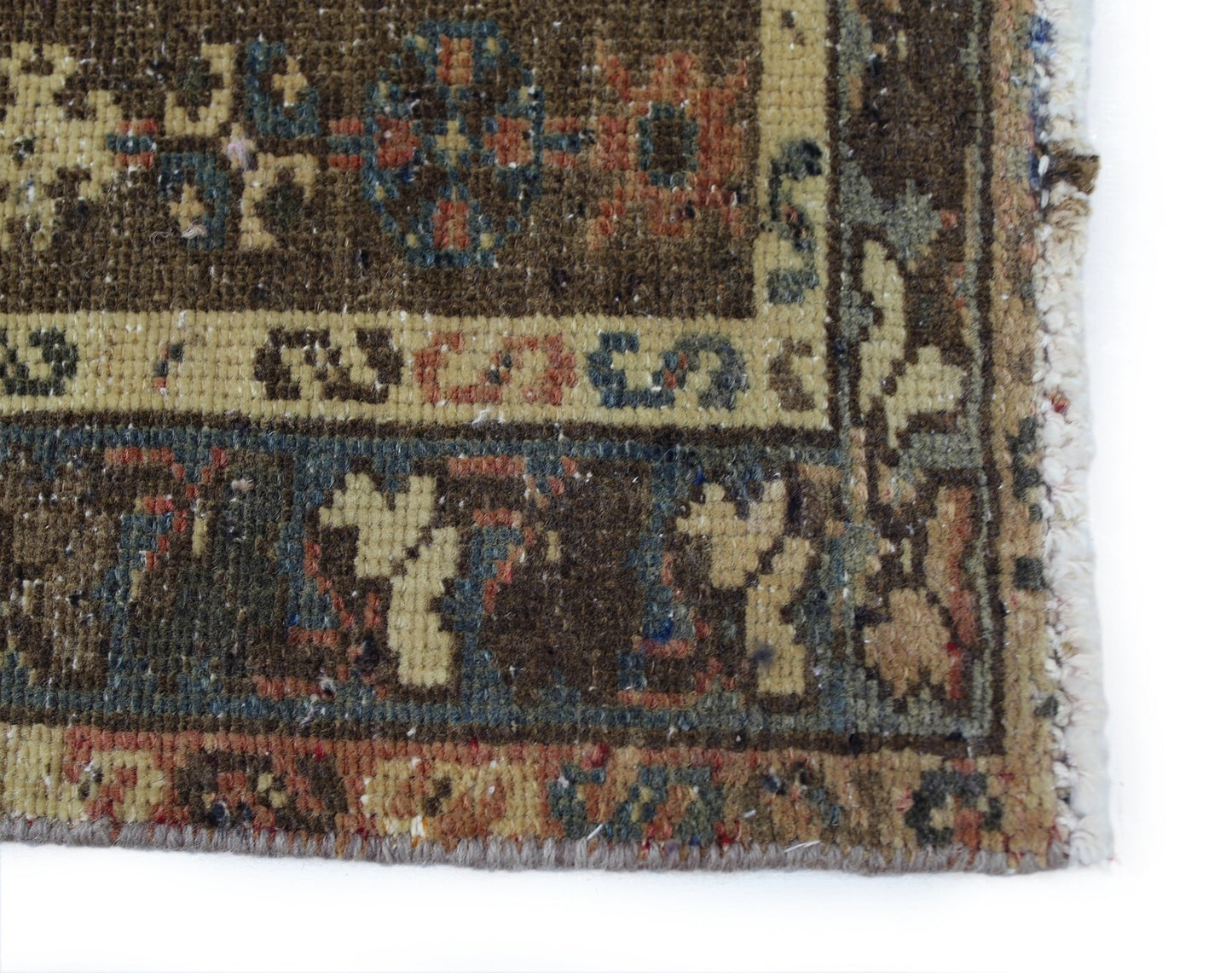 A close-up of a vintage Persian Mazlaghan rug featuring geometric patterns in earthy tones.