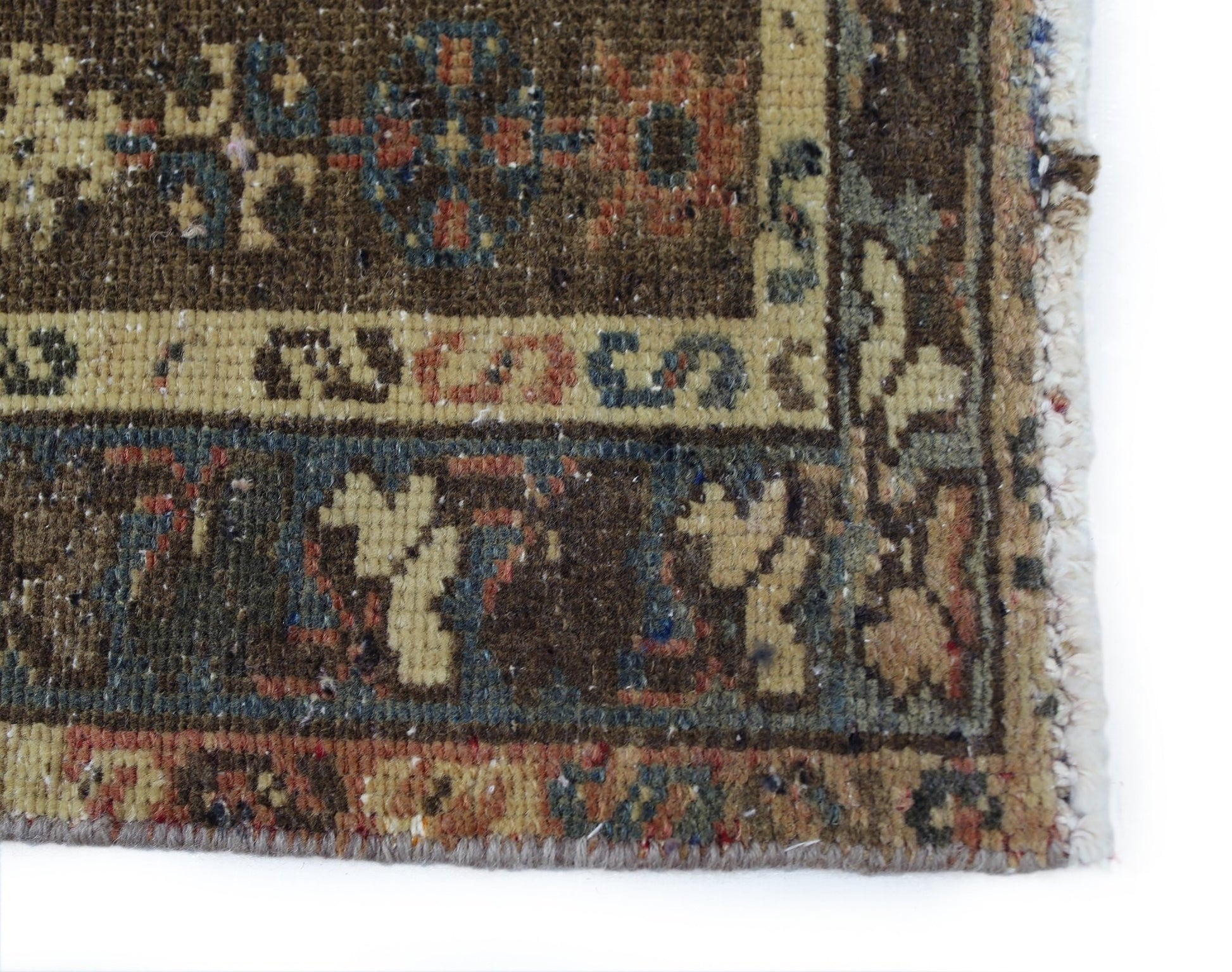A close-up of a vintage Persian Mazlaghan rug featuring geometric patterns in earthy tones.