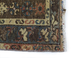 A close-up of a vintage Persian Mazlaghan rug featuring geometric patterns in earthy tones.