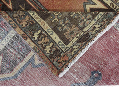 A corner of a vintage Persian Mazlaghan rug showing its intricate geometric pattern and wool pile.