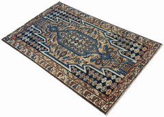 A vintage handwoven Persian Mazlaghan rug featuring a geometric pattern in blue and tan tones.