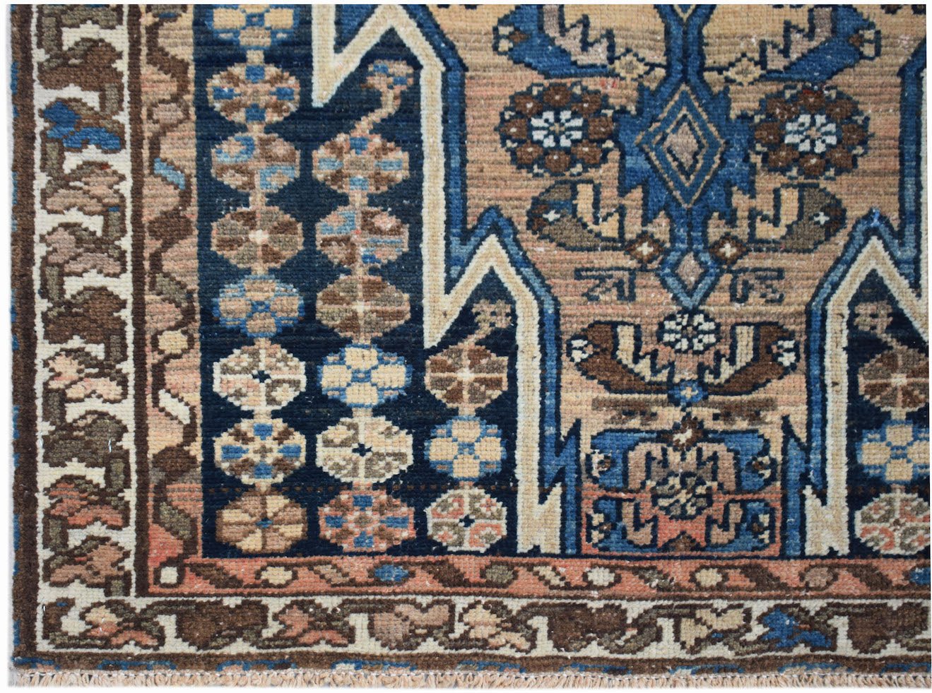 A vintage Persian Mazlaghan rug featuring geometric floral patterns in blue, brown, and tan.