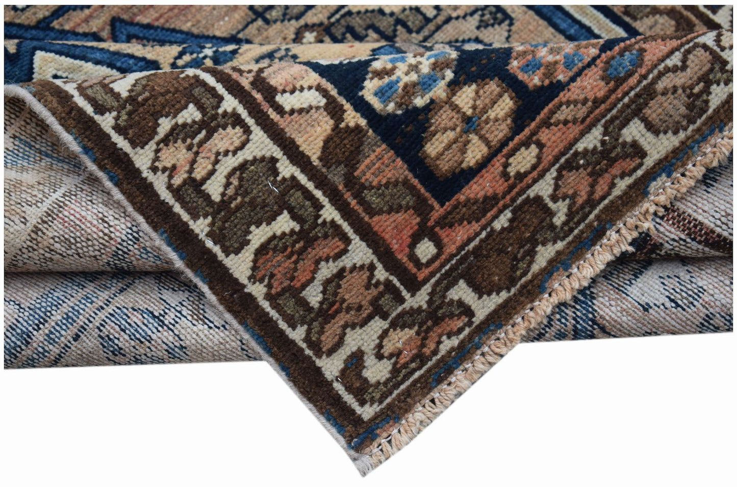 A vintage handwoven Persian Mazlaghan rug featuring geometric patterns in blue, brown, and tan.