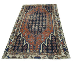 A vintage Persian Mazlaghan rug featuring a geometric navy and orange pattern on a cream border.
