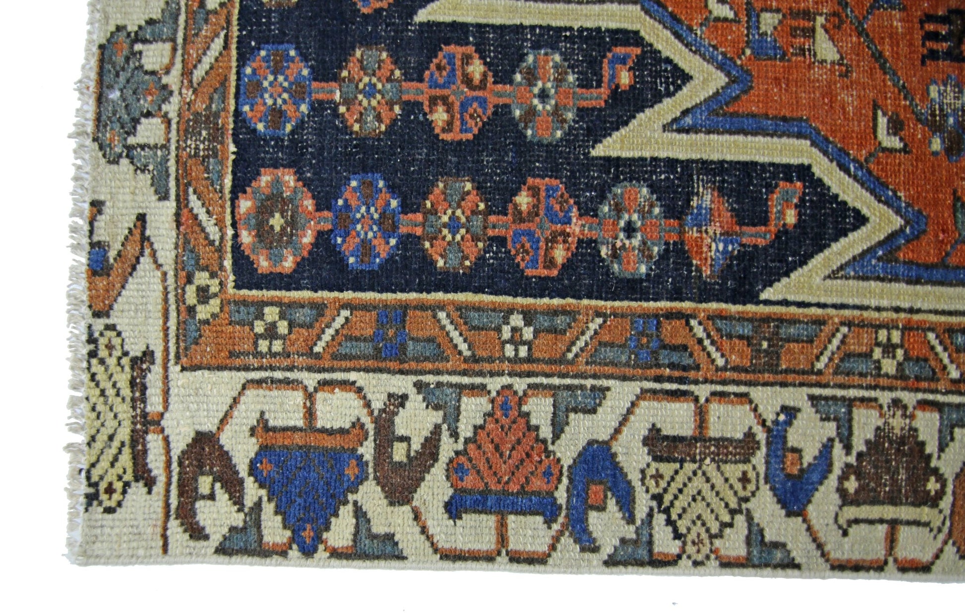 A vintage Persian Mazlaghan rug featuring geometric patterns in blue, orange, and cream wool.