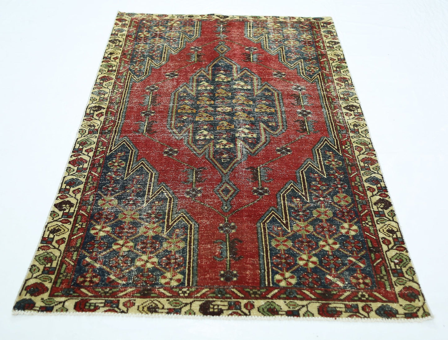 A vintage Persian Mazlaghan rug featuring a central geometric medallion on a red field.