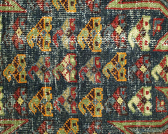 A close-up of a vintage Persian Mazlaghan rug featuring a repeating geometric pattern in wool.