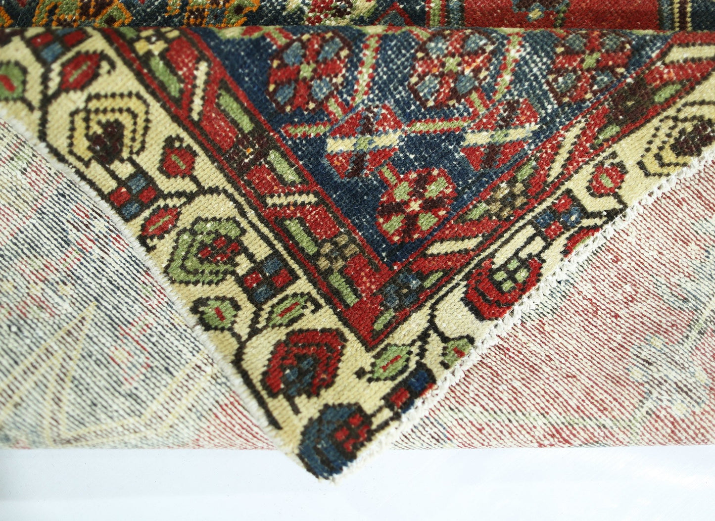 A corner of a vintage Persian Mazlaghan rug showing its intricate floral pattern and wool pile.