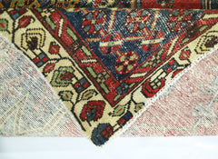 A corner of a vintage Persian Mazlaghan rug showing its intricate floral pattern and wool pile.