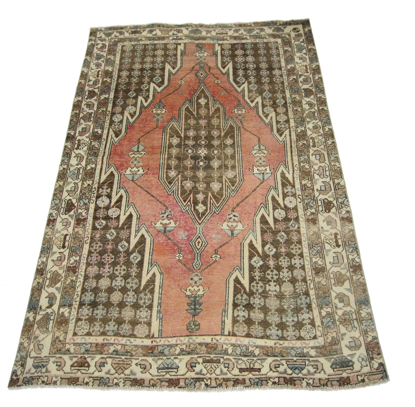 A vintage Persian Mazlaghan rug featuring a geometric diamond medallion on a pink and brown field.