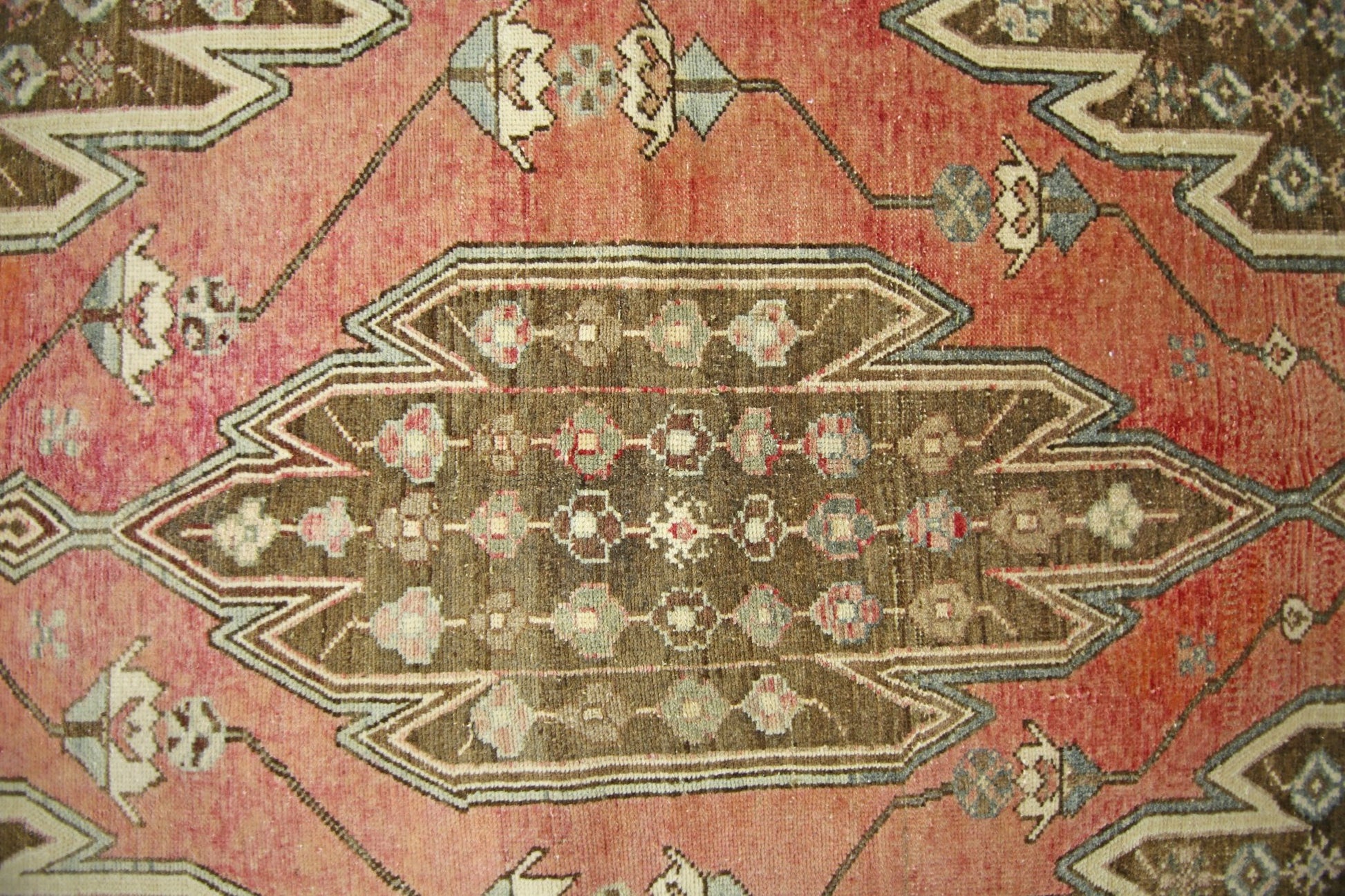 A vintage Persian Mazlaghan rug featuring a central brown geometric medallion on a red field.