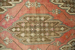 A vintage Persian Mazlaghan rug featuring a central brown geometric medallion on a red field.