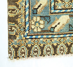 A corner detail of a vintage Persian Mazlaghan rug featuring geometric patterns in blue and brown.