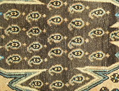 A close-up of a vintage Persian Mazlaghan rug featuring a dark brown field with repeating paisley.