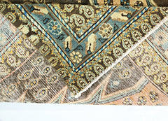 A folded vintage Persian Mazlaghan rug featuring intricate geometric patterns in blue, brown, and tan.