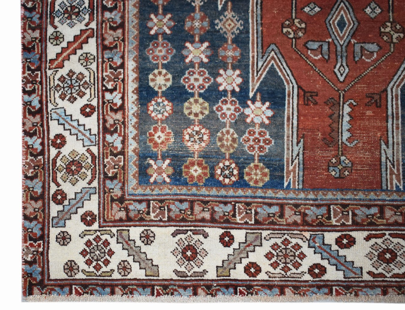 A vintage Persian Mazlaghan rug featuring a geometric floral pattern in red, blue, and cream.