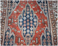 A vintage Persian Mazlaghan rug featuring a geometric blue medallion on a red field.