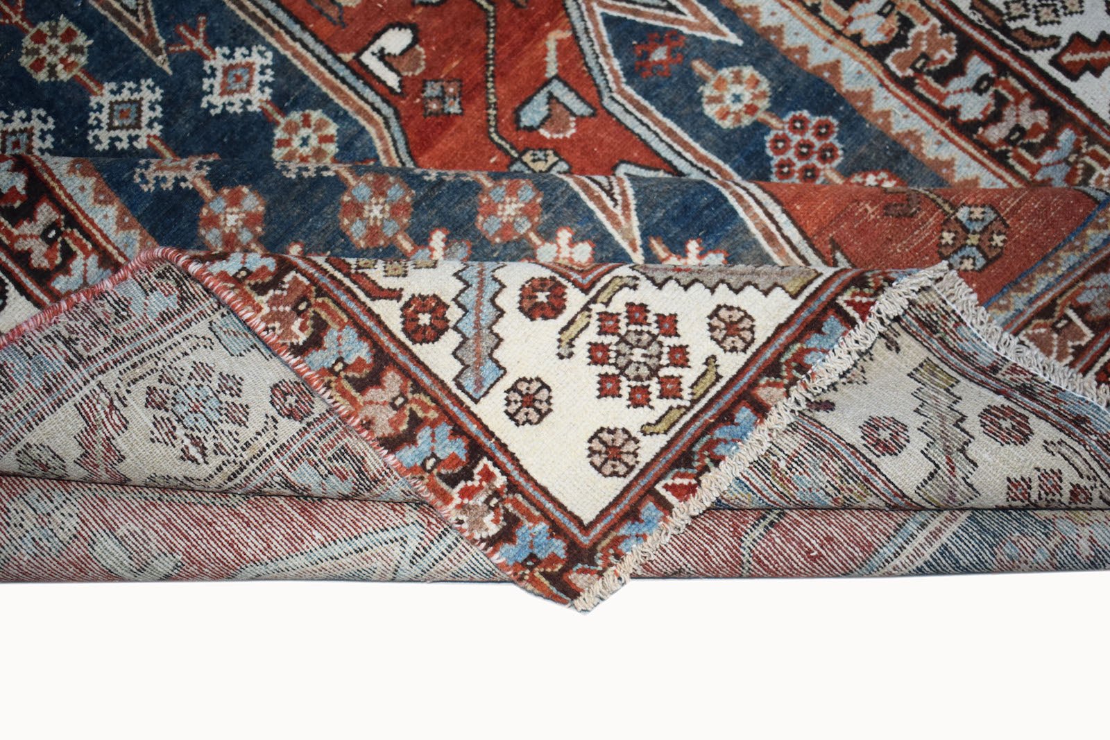A vintage handwoven Persian Mazlaghan rug featuring geometric floral patterns in red, blue, and cream.