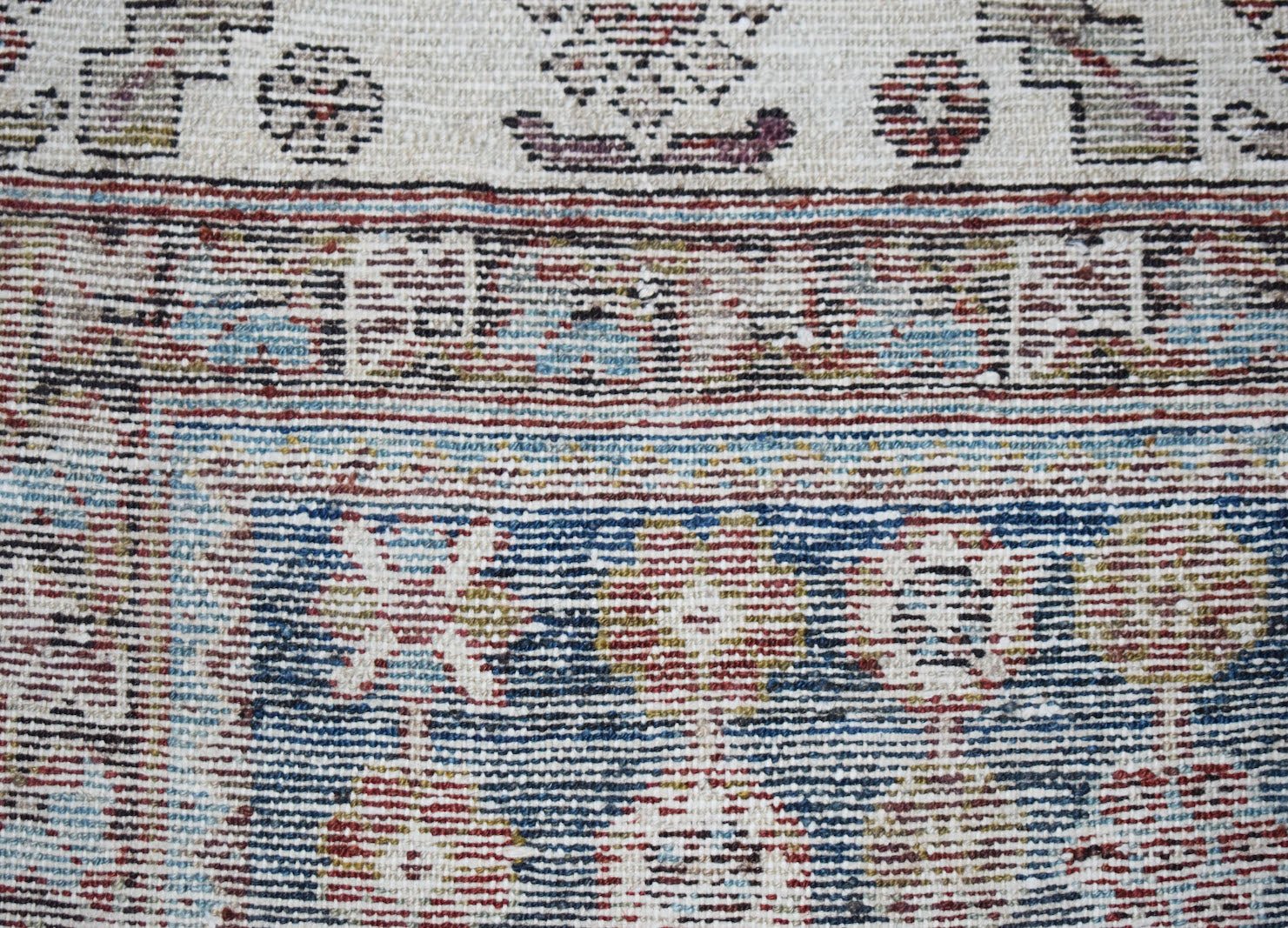 A close-up of a vintage Persian Mazlaghan rug featuring intricate geometric patterns in wool.