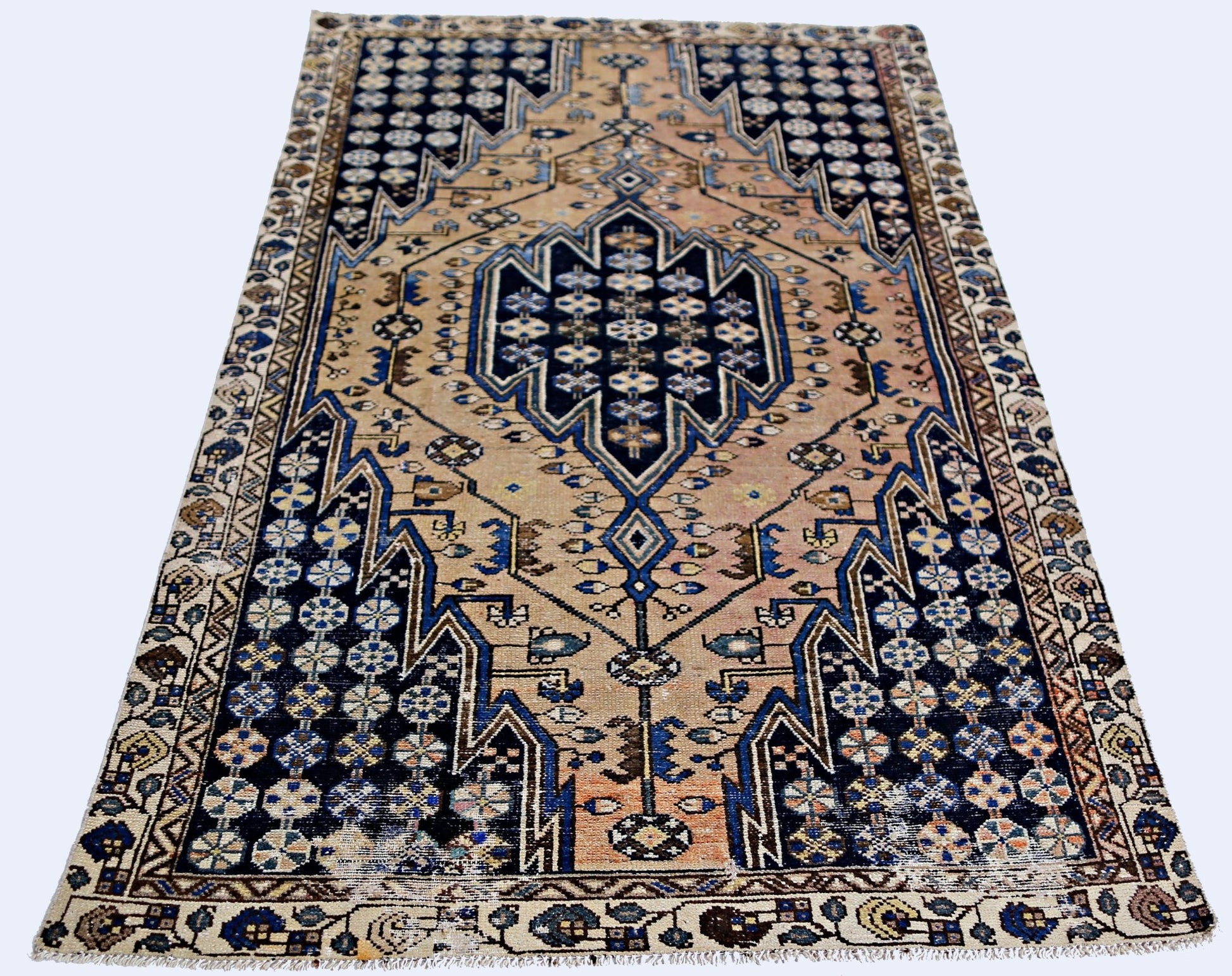 A vintage Persian Mazlaghan rug featuring a geometric blue medallion on a tan field.