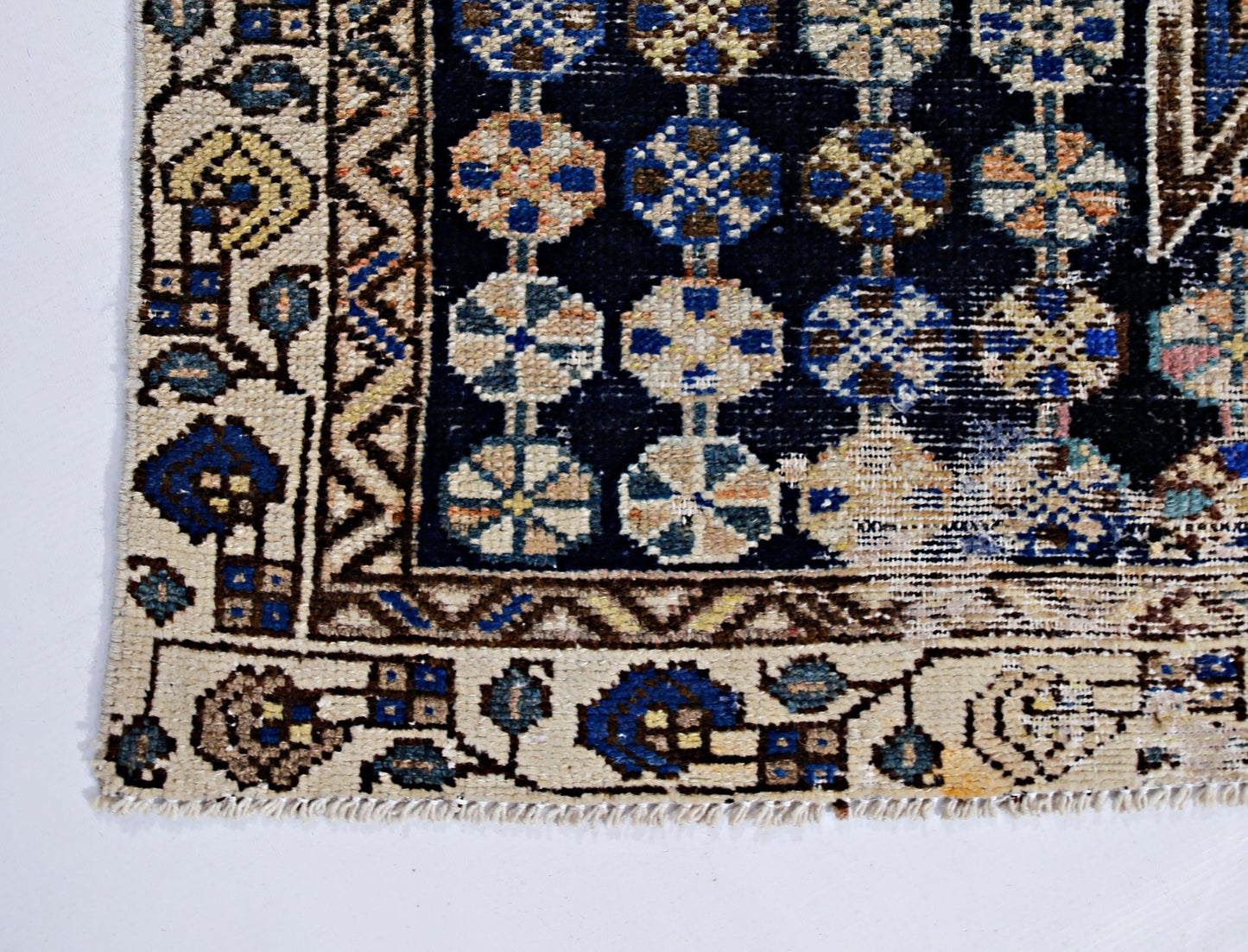 A vintage Persian Mazlaghan rug featuring a dark blue field with geometric floral motifs.