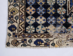 A vintage Persian Mazlaghan rug featuring a dark blue field with geometric floral motifs.