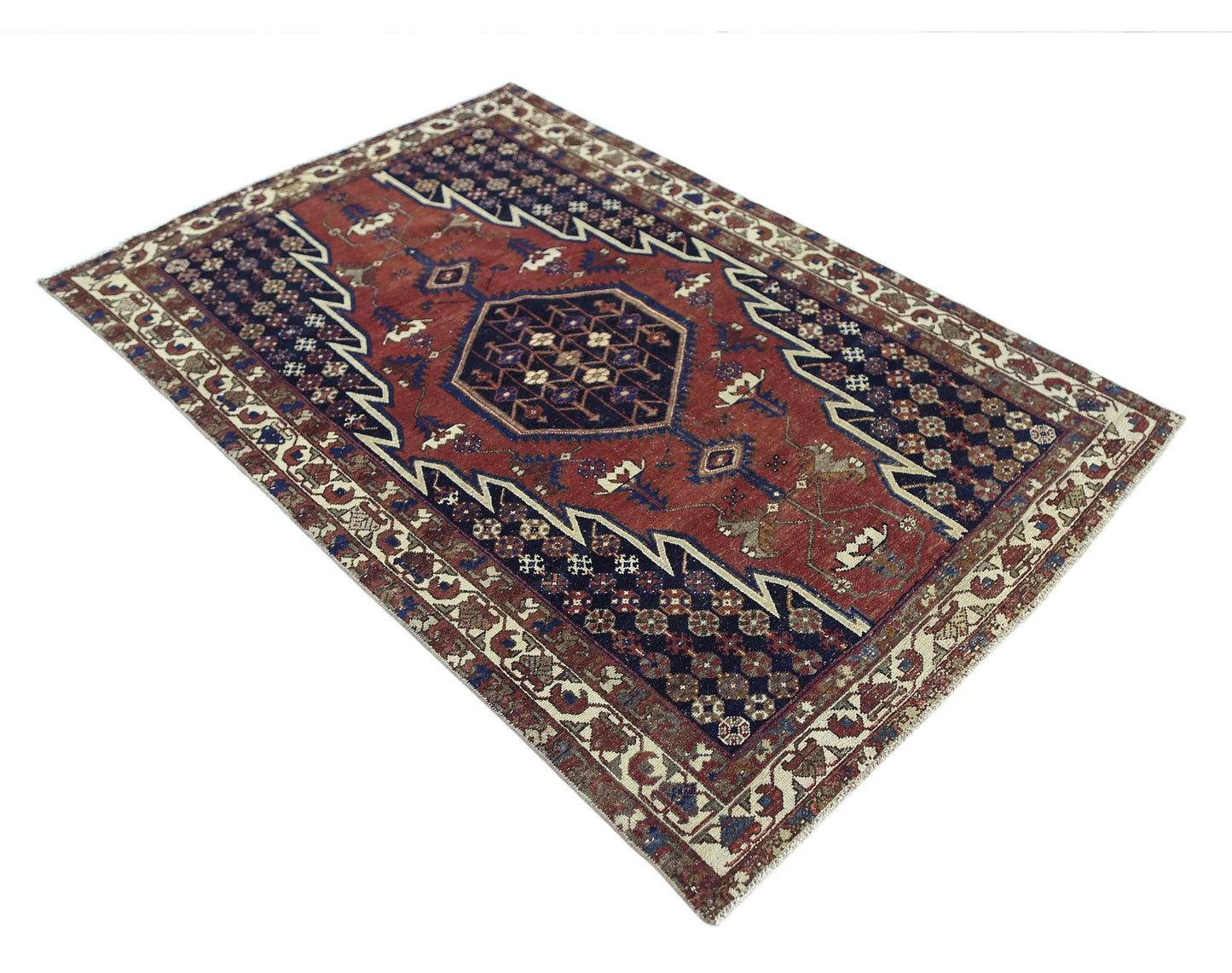 A vintage Persian Mazlaghan rug featuring a geometric central medallion on a red and blue field.