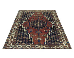 A vintage Persian Mazlaghan rug featuring a geometric medallion on a red and navy field.