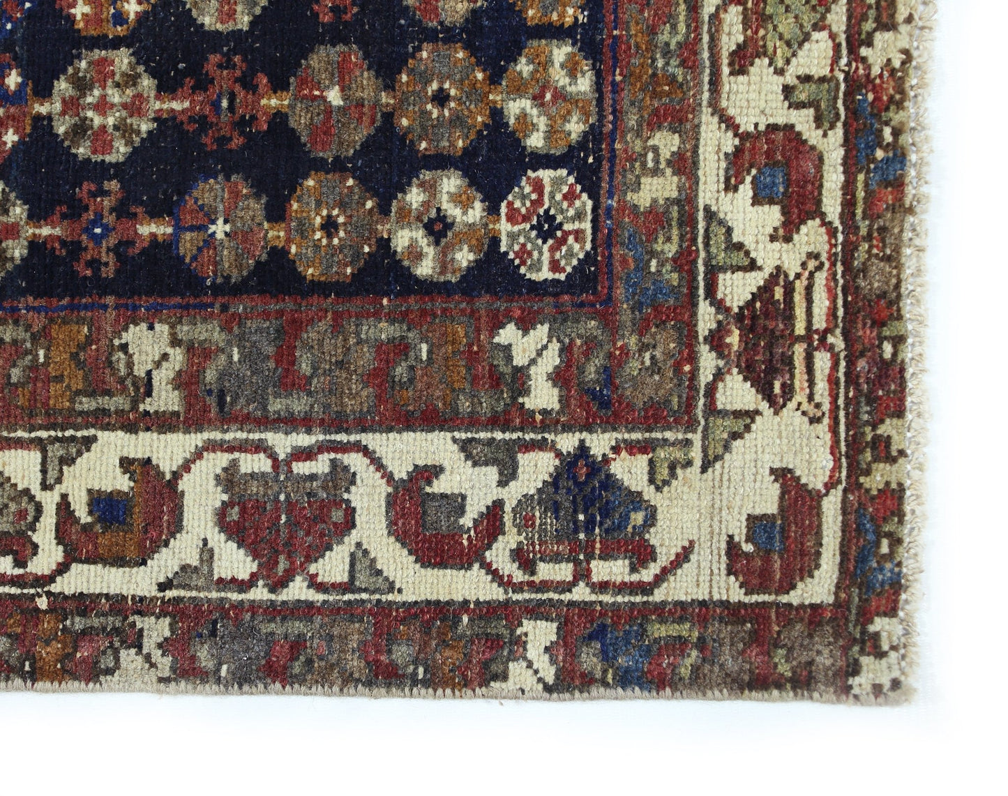 A vintage Persian Mazlaghan rug featuring a dark blue field with geometric floral motifs.