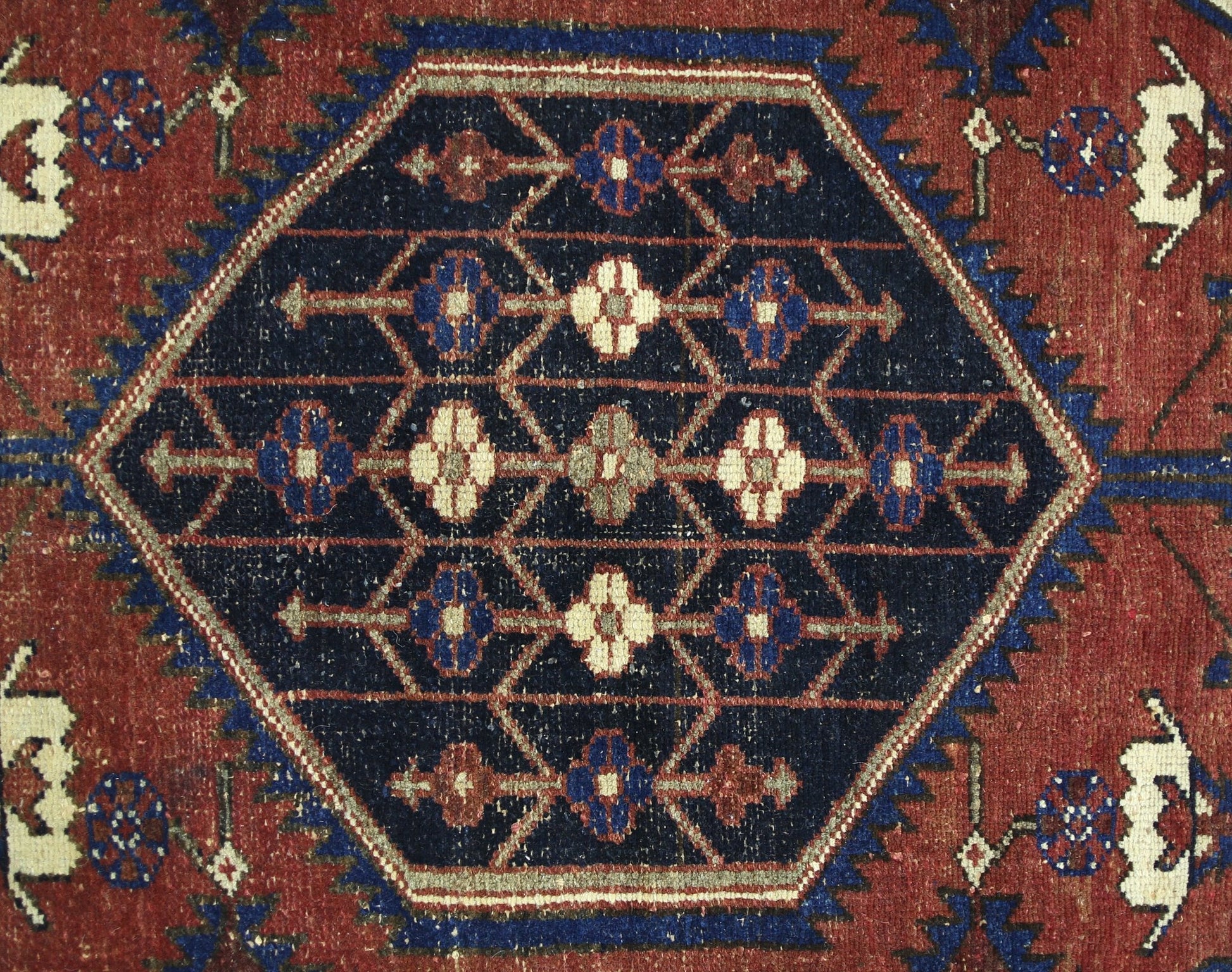A vintage Persian Mazlaghan rug featuring a central dark blue hexagon with geometric floral motifs.