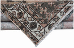 A folded vintage Persian Mazlaghan rug featuring a geometric pattern in muted pink and brown tones.