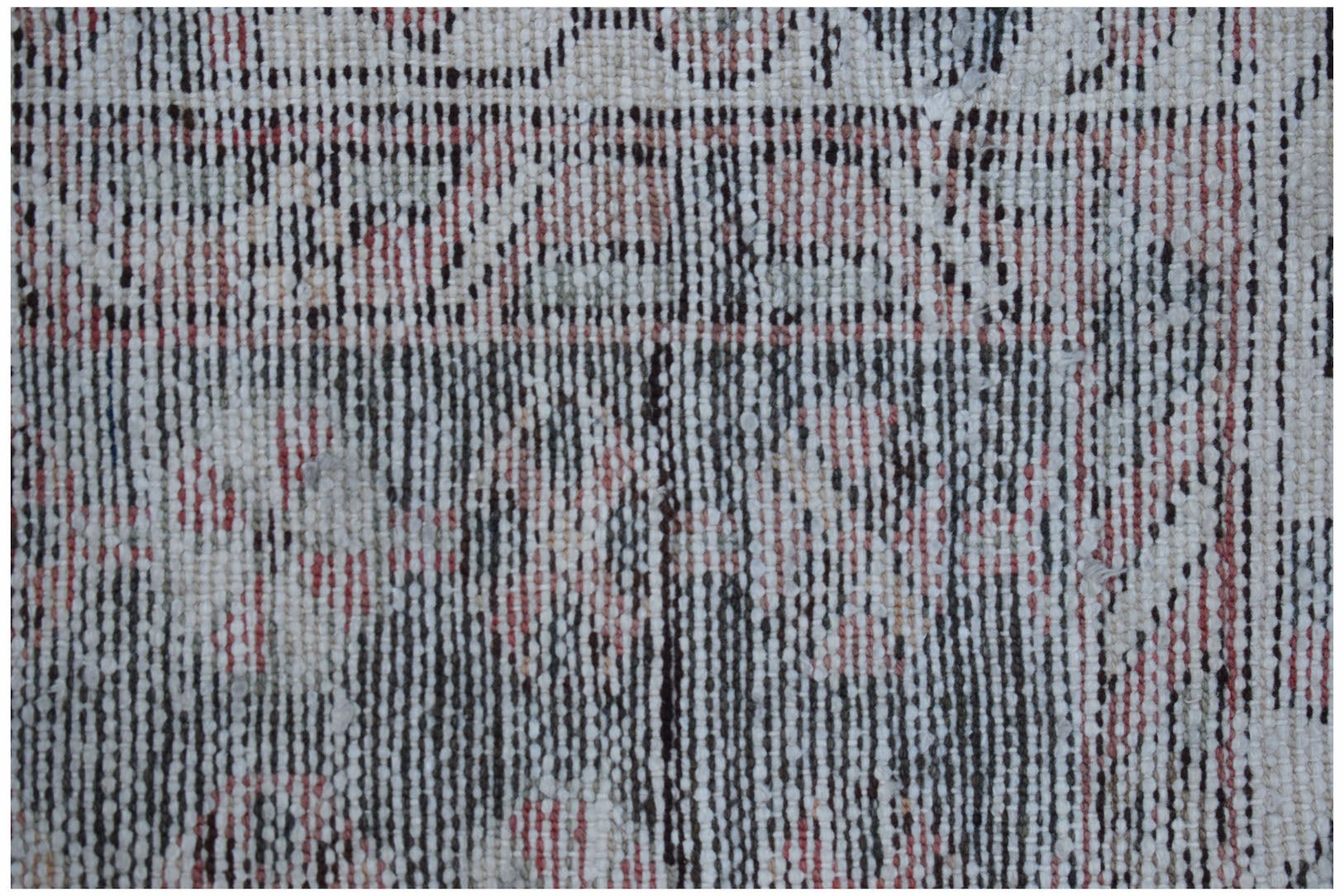 A close-up view of a vintage Persian Mazlaghan rug featuring a faded geometric pattern in wool.