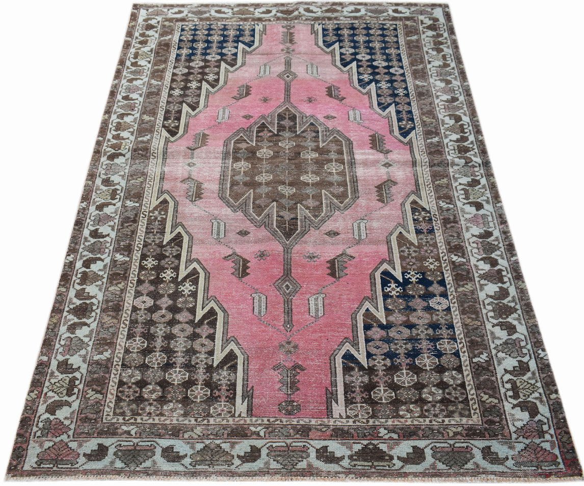 A vintage handwoven Persian Mazlaghan rug featuring a pink central medallion on a dark background.