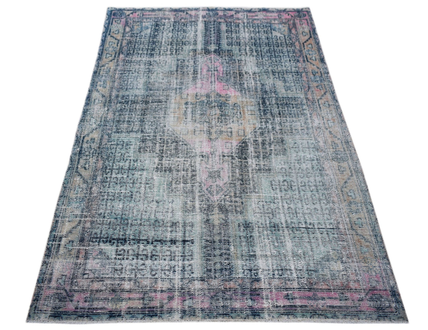 A vintage Persian rug featuring a distressed blue and pink medallion pattern on a faded background.