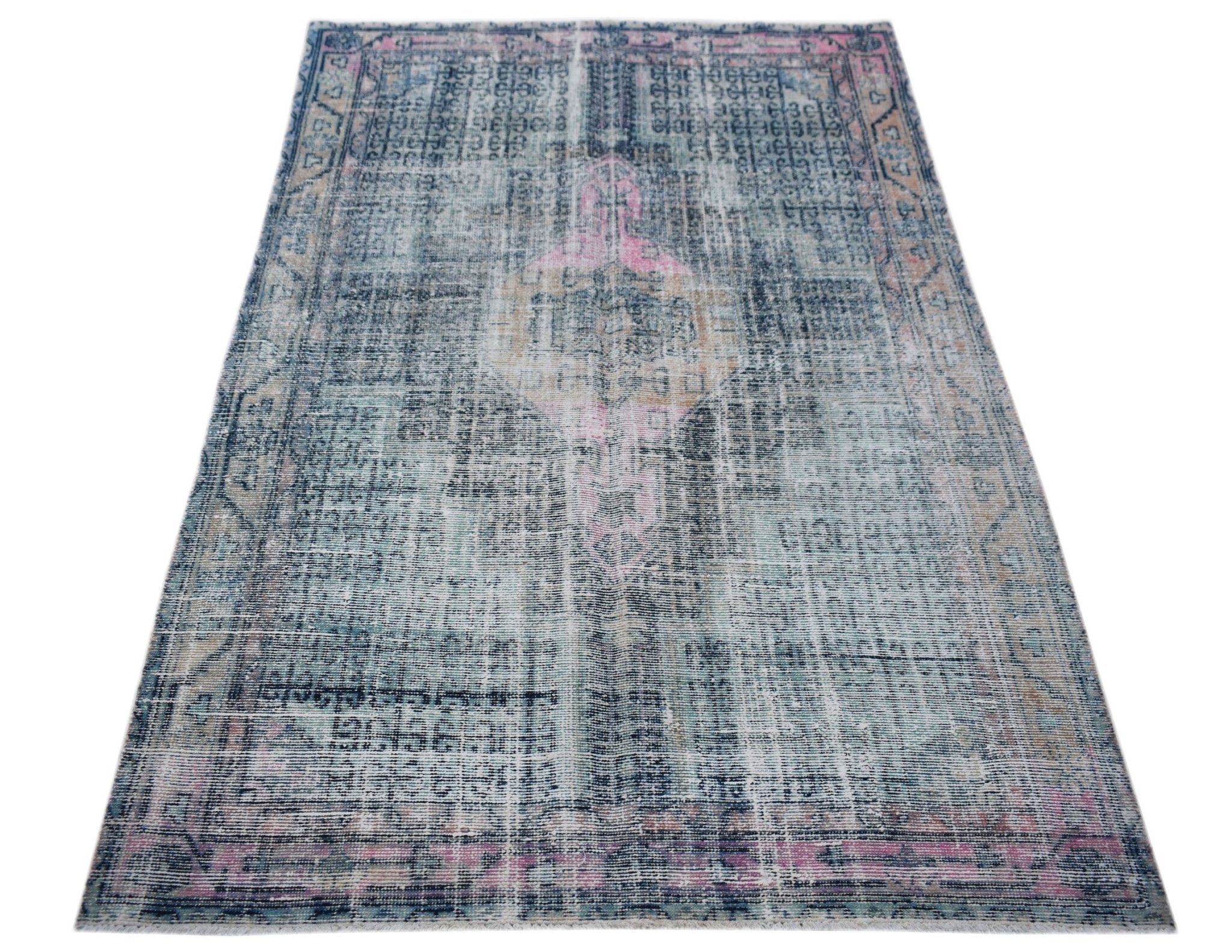 A vintage Persian rug featuring a distressed blue and pink medallion pattern on a faded background.