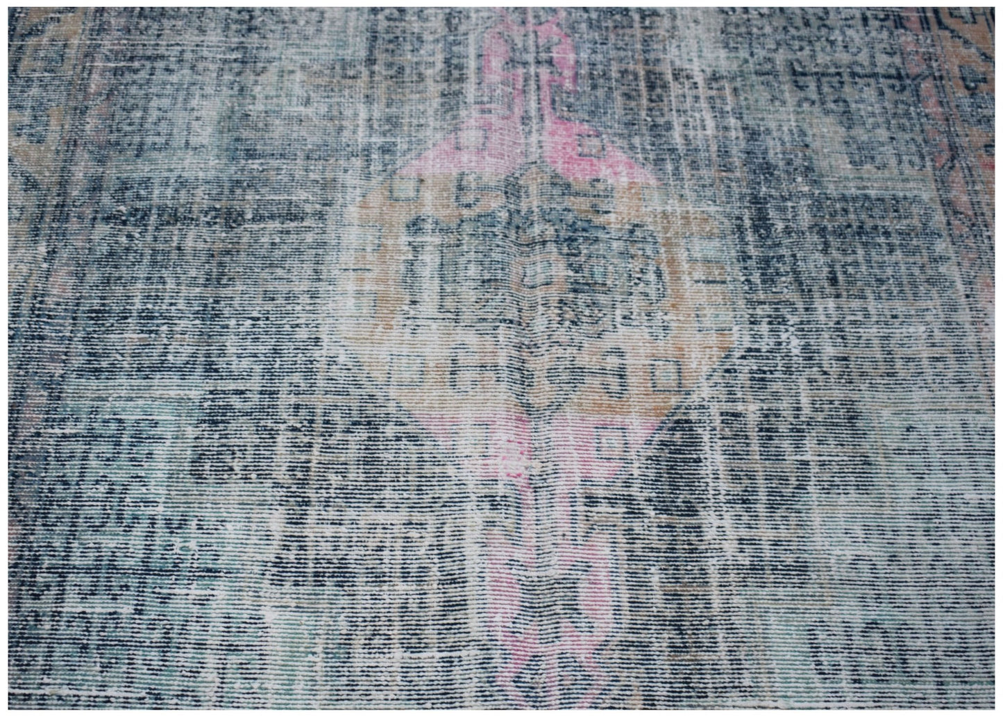 A vintage Persian rug featuring a distressed blue, pink, and tan geometric medallion pattern.