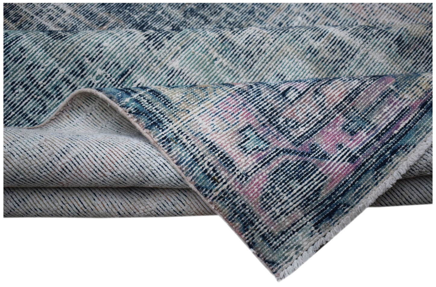 A vintage handwoven Persian rug featuring a distressed blue and pink floral pattern.