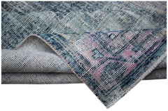 A vintage handwoven Persian rug featuring a distressed blue and pink floral pattern.