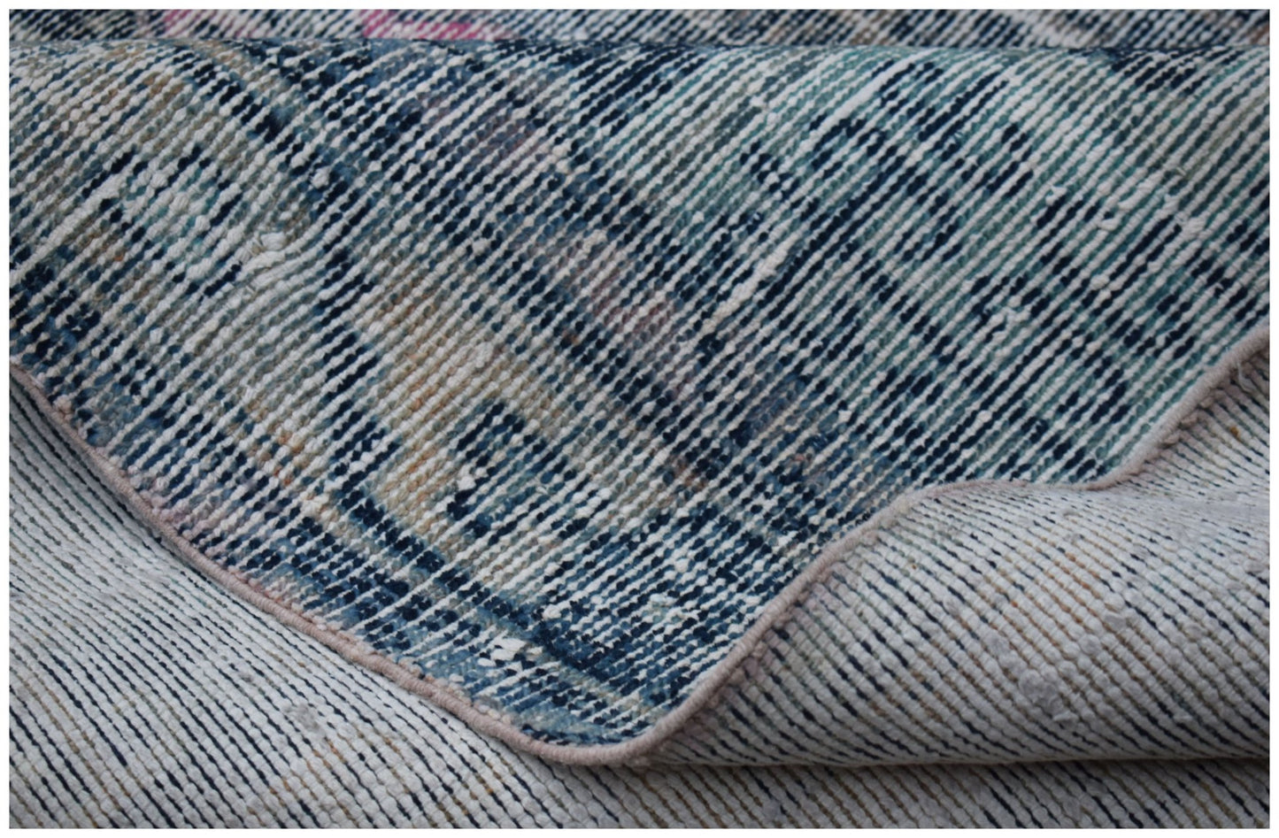 A folded vintage Persian rug featuring a distressed blue and cream patterned wool weave.