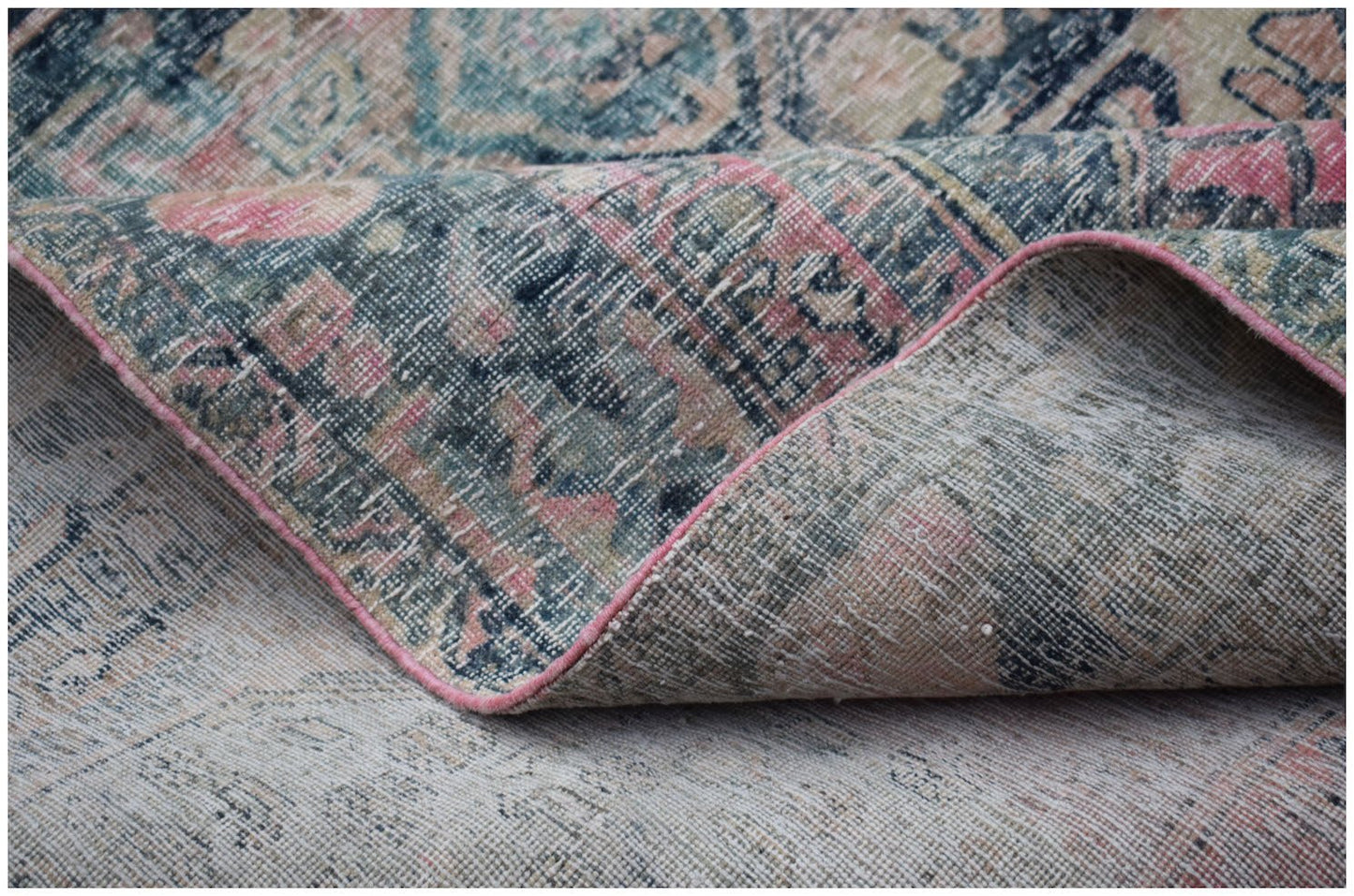 A vintage Persian Mazlaghan rug with a faded floral pattern in blue, pink, and cream tones.